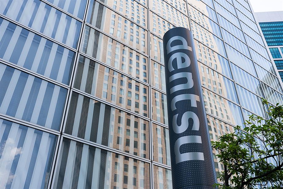 Dentsu logo in front of a glass building